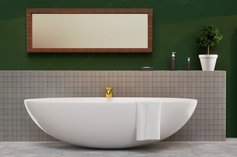 White bathtub with gold faucet in front of green wall