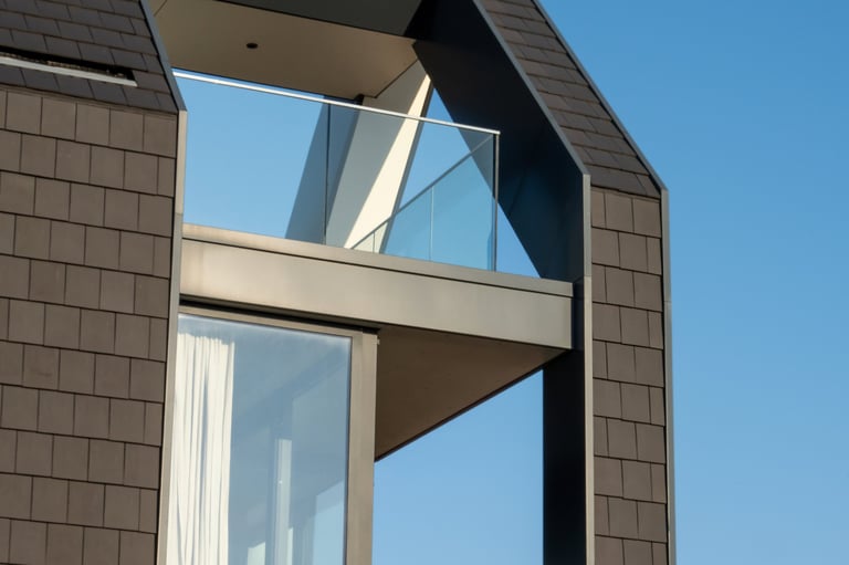 Modern house exterior with glass balcony and dark tile cladding