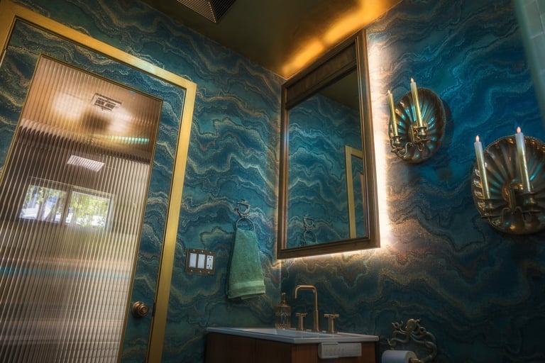 Ocean-inspired bathroom with teal wallpaper and gold accents
